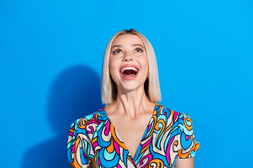 Portrait of impressed gorgeous girl wear stylish shirt straing at amazing offer empty space isolated on vivid blue color background.