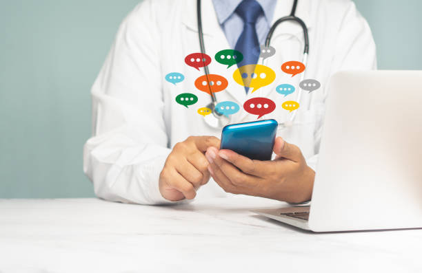 istock Doctor in uniform using a smartphone with colorful chat icons on application social media while sitting in the hospital. 1957237048