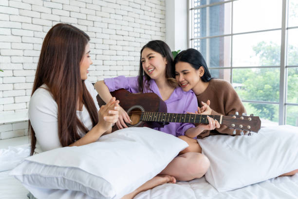 istock Friends are jamming together on a bed, singing and playing guitar. 1957252024