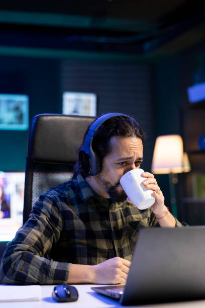 Guy wears headphones and drinks coffee