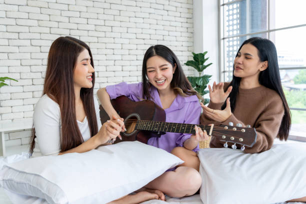 istock Friends are jamming together on a bed, singing and playing guitar. 1957252058