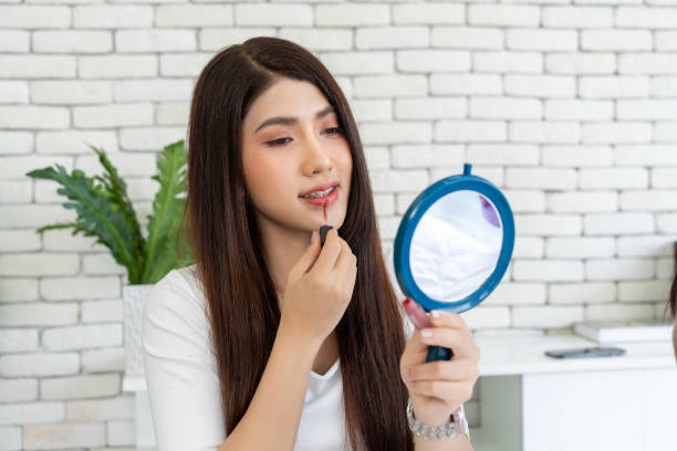istock Young woman applying makeup while sitting on bed and looking in a mirror 1957253689