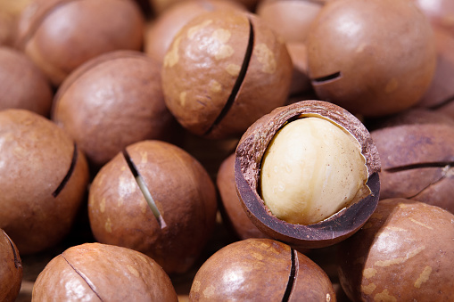 Macadamia Whole And Chopped Background. Unpeeled and Peeled Nuts Texture. Small Depth of Field