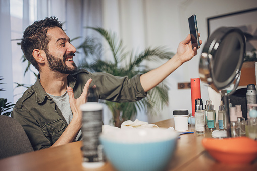 Man using mobile phone while doing his facial routine