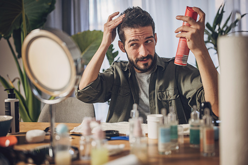 Man styling His Hair at home and putting hair spray