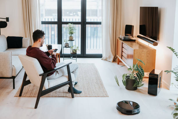 istock Man taking time off, while the robot vacuum works for him 1957273192