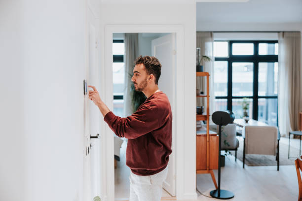 istock Man using smart thermostat in his modern home 1957273215