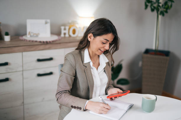 istock Businesswoman in a modern home office making notes in a notebook 1957275360