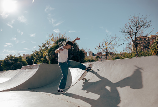 Active skateboarder jumping and performing a trick in a ramp of a skate park