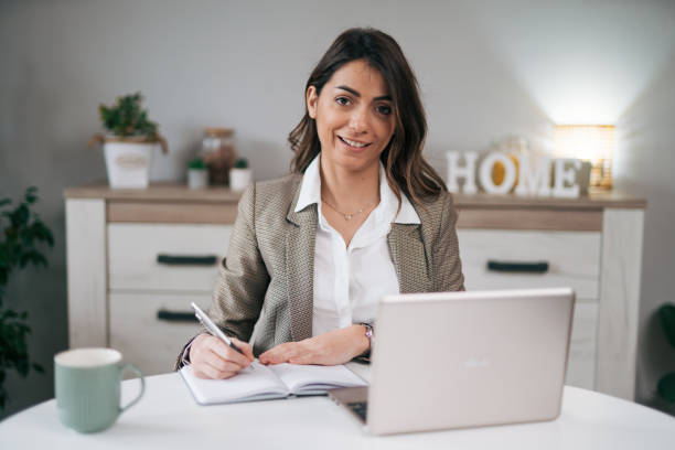 istock Businesswoman in a modern home office making notes in a notebook 1957275883