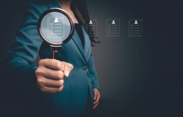 istock HR manager using magnifying glass focus to virtual human resource icons for employee recruitment. Check resume, Screening employee information and job applicants. Human resources management concept. 1957278557