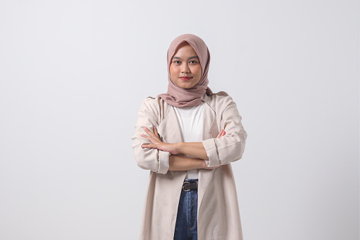 Portrait of young successful Asian hijab woman in casual suit looking at camera, holding hands crossed folded. Isolated image on white background