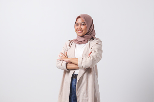 Portrait of young successful Asian hijab woman in casual suit looking at camera, holding hands crossed folded. Isolated image on white background