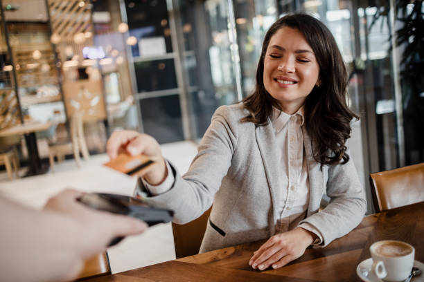 The guest in the restaurant pays contactless with a payment card An elegant business woman pays in a cafe through a contactless terminal using a bank card restaurant table card stock pictures, royalty-free photos & images
