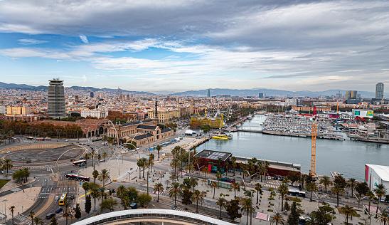 Aerial view on Barcelona skyline and marina, mountain ridges in distance under the moody sky