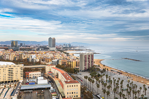 Aerial view on Barcelona cityscape and coastline with resorts and beach under the moody sky