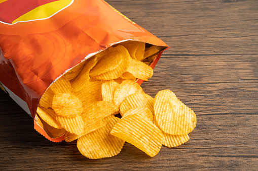 Potato chips, delicious BBQ seasoning spicy for crips, thin slice deep fried snack fast food in open bag.