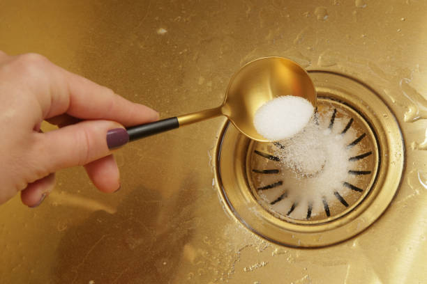 istock Cleaning kitchen sink with bakIng soda to keep sinks draining well and prevent clogs. Safe, effective, cheap, natural solution for clogged drains. 1957315385