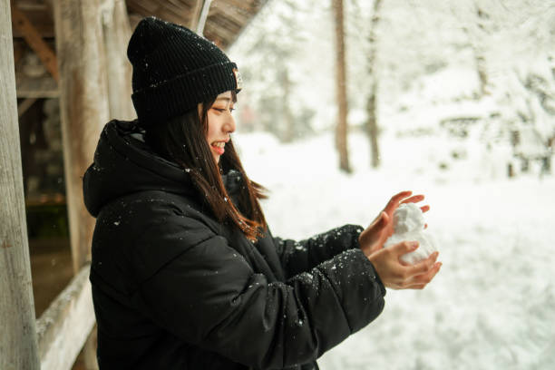 View of Young Handsome Man in Warm Clothing Throwing a Snowball During a Winter Day