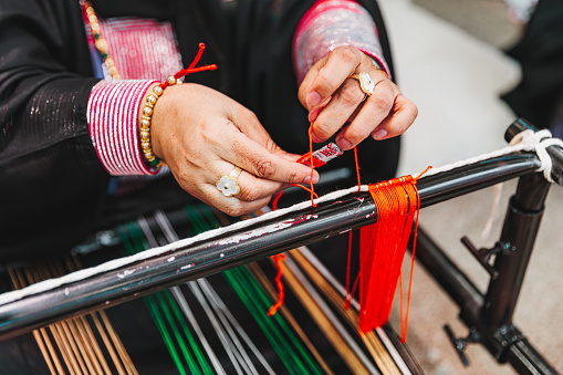 Female hands coiling fabric strings on spool, work on traditional weaving loom, crafts and cultures
