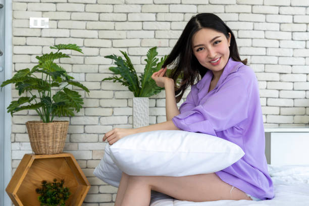 istock Bedtime Elegance, Young Woman Poses with Pillows on Bed in Bedroom Setting 1957323639