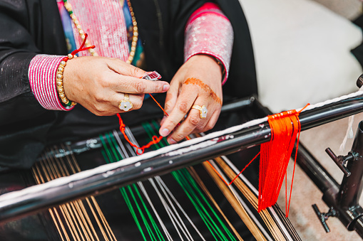 Female hands working with fabric strings and spooling, work on traditional weaving loom, crafts and cultures