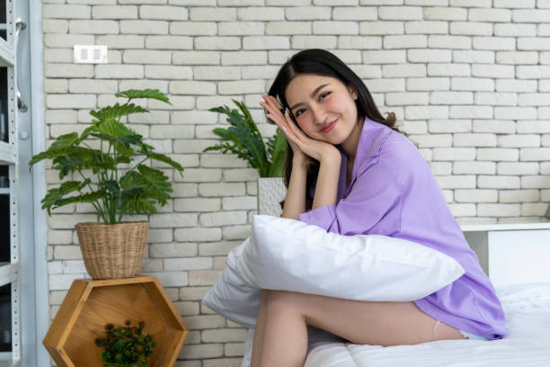 istock Bedtime Elegance, Young Woman Poses with Pillows on Bed in Bedroom Setting 1957325253