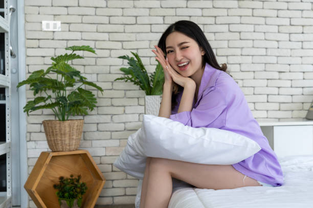 Bedtime Elegance, Young Woman Poses with Pillows on Bed in Bedroom Setting