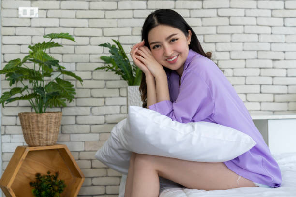 istock Bedtime Elegance, Young Woman Poses with Pillows on Bed in Bedroom Setting 1957325310