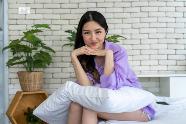 istock Bedtime Elegance, Young Woman Poses with Pillows on Bed in Bedroom Setting 1957325314