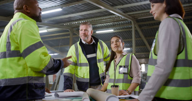 istock Architecture people, blueprint and teamwork at construction site, warehouse or building development with carpenter. Man, women or project manager talking of floor plan, collaboration and engineering 1957349329