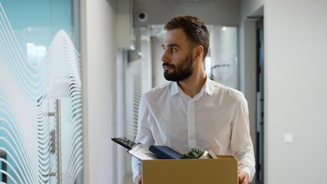 Dismissed worker leaving or resign or dismiss from job, man carry personal box walking out from office