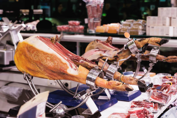 Food market stall in Barcelona, cured ham Jamon Ibérico on special stand, cut into slices for sale