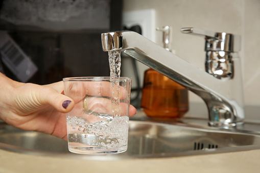Filling up a glass with fresh drinking water from kitchen faucet