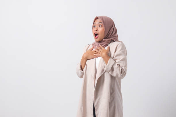 Portrait of frightened Asian hijab woman in casual suit making shocked hand gesture, showing surprised and scared expression. Isolated image on white background stock photo