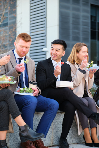 Group of Multiethnic businesspeople having lunch outdoor from office building. Healthy eating.