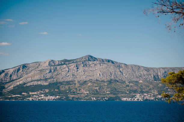Deep sea stretching out in front of high mountains and creating beautiful contrast between blue water and majestic rocky peaks. Picturesque scenery of Brac island, Croatia.