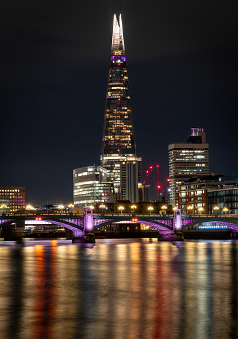 London. UK- 01.20.2024. A long exposure night view of The Shard with light reflections on the Thames River.