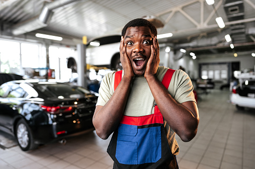 African man mechanic in uniform at the car repair station, portrait, close up
