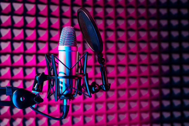 istock Professional studio microphone against acoustic foam panel background in neon light 1957408526