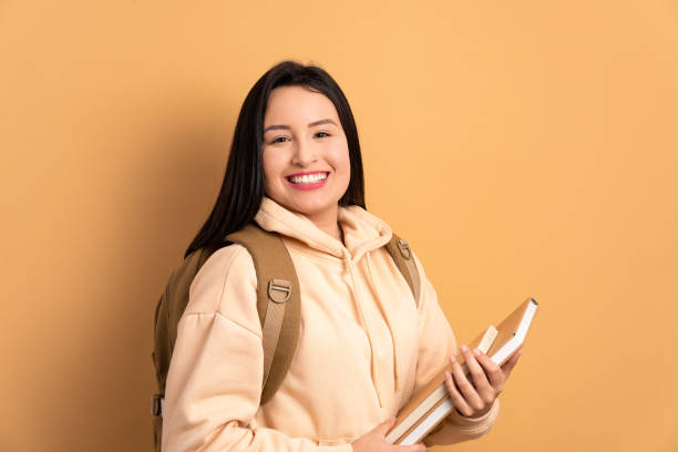 istock cheerful woman holding academy book and smiling 1957419083
