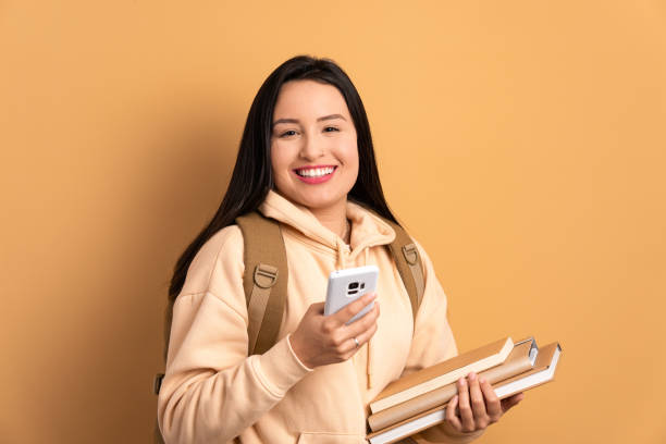 istock happy student smiling and holding mobile phone 1957419611