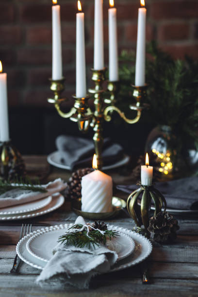istock Rustic elegant table decor for christmas family dinner. Center piece with white candle, pine cone, fir tree branches. Zero waste eco-friendly home decoration. Cozy atmosphere, wooden background. 1957425716