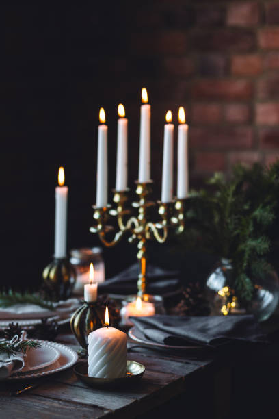 istock Rustic elegant table decor for christmas family dinner. Center piece with white candle, pine cone, fir tree branches. Zero waste eco-friendly home decoration. Cozy atmosphere, wooden background. 1957426285