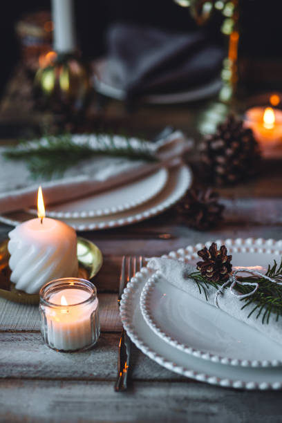 istock Rustic elegant table decor for christmas family dinner. Center piece with white candle, pine cone, fir tree branches. Zero waste eco-friendly home decoration. Cozy atmosphere, wooden background. 1957426810