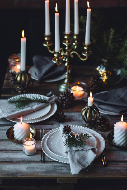istock Rustic elegant table decor for christmas family dinner. Center piece with white candle, pine cone, fir tree branches. Zero waste eco-friendly home decoration. Cozy atmosphere, wooden background. 1957431774