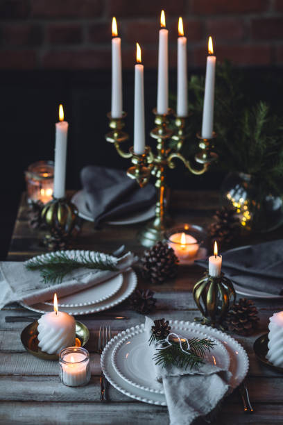 istock Rustic elegant table decor for christmas family dinner. Center piece with white candle, pine cone, fir tree branches. Zero waste eco-friendly home decoration. Cozy atmosphere, wooden background. 1957432333