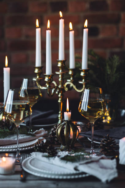 istock Beautiful table setting for family Christmas dinner at home. Cozy atmosphere, candlelight. Wine glasses, vintage chandelier, elegant interior. Fir tree branches, wooden furniture, dark, bokeh 1957433502
