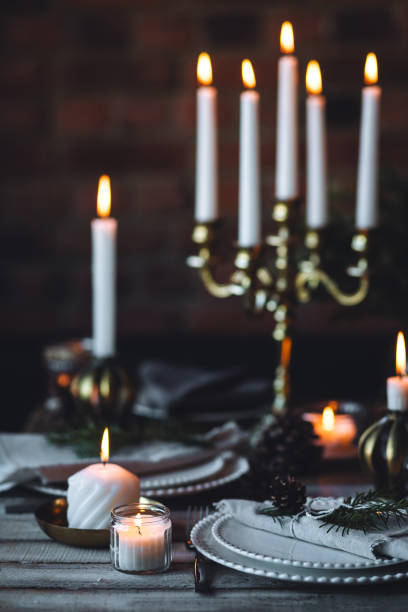 istock Rustic elegant table decor for christmas family dinner. Center piece with white candle, pine cone, fir tree branches. Zero waste eco-friendly home decoration. Cozy atmosphere, wooden background. 1957434587