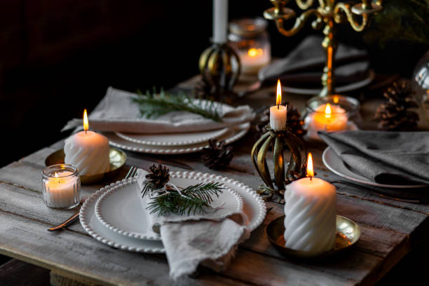 istock Rustic elegant table decor for christmas family dinner. Center piece with white candle, pine cone, fir tree branches. Zero waste eco-friendly home decoration. Cozy atmosphere, wooden background. 1957435106